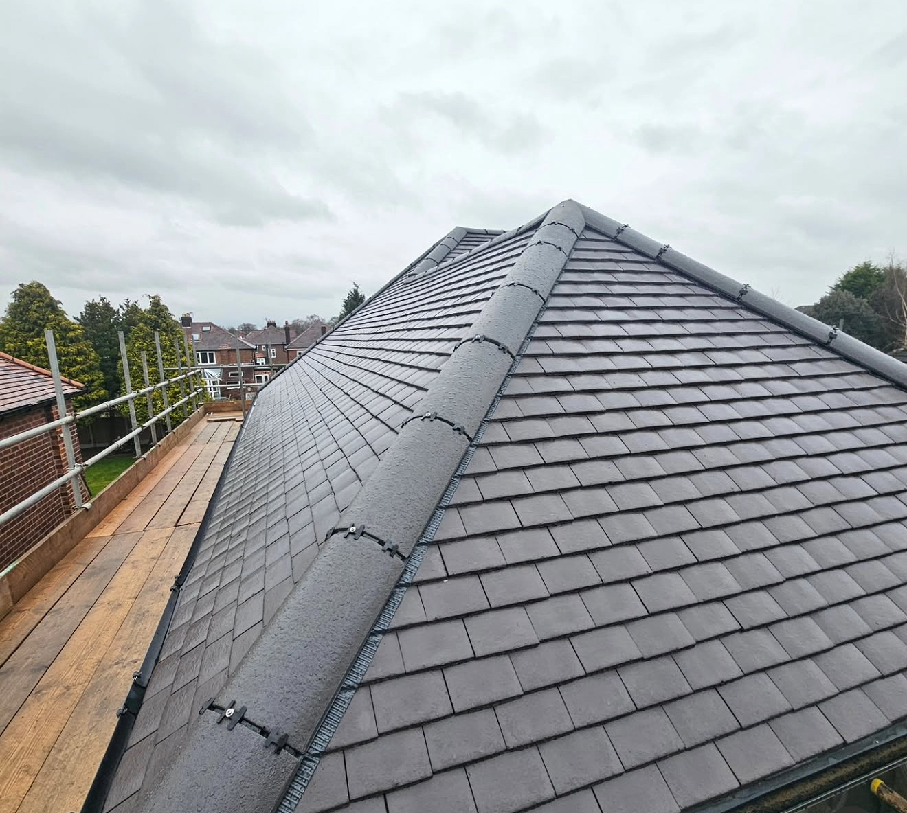 Newly completed grey slate hipped roof with ridge tiles, viewed from scaffolding