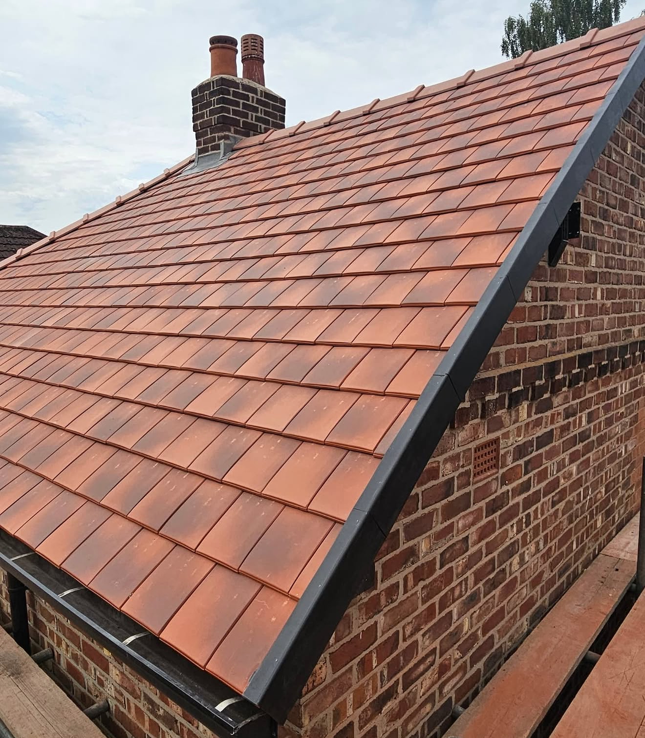 New terracotta clay tiled roof with dry verge and repointed chimney